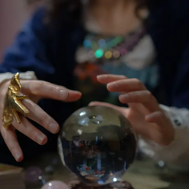 A captivating fortune teller engaging in divination with a crystal ball and tarot cards, symbolizing mysticism.