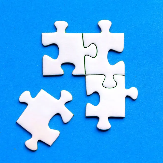 White jigsaw puzzle pieces against a solid blue background, showcasing a flat lay arrangement.