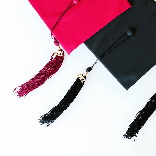Vibrant red and black graduation caps with 2024 tassels on a white background.