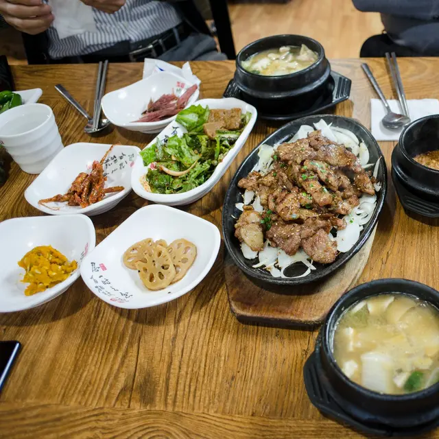 An overhead view of various Korean dishes served on a wooden table, showcasing traditional cuisine.