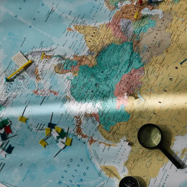 Exploration tools, including a compass and magnifying glass, placed on a colorful world map.