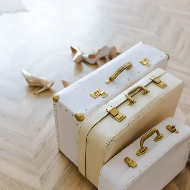 Stylish vintage suitcases with gold accents on a wooden floor, ideal for travel-themed decor.