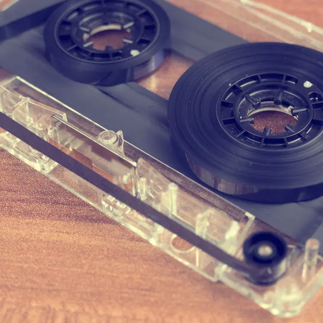 Detailed close-up of a retro audio cassette tape on a wooden surface.