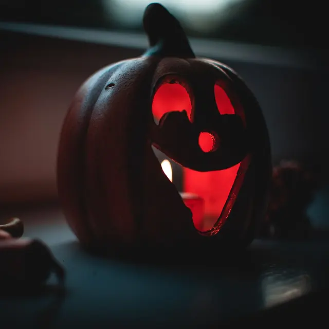 A carved pumpkin jack-o'-lantern glowing with candlelight, perfect for Halloween ambiance.
